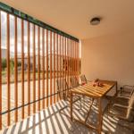 Terrace with wooden table and chairs, separated by wooden railing.
