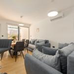 Living and dining area with sofa, table and chairs, view to balcony.