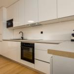 Modern kitchen with white cabinets, stainless steel countertop, and built-in oven.