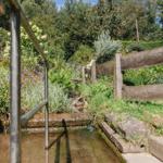 Wasserlauf mit Metallgeländer und Holzgeländer durch grüne Landschaft