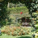 Garten mit Sitzbereich unter Pavillon, umgeben von üppiger Vegetation.