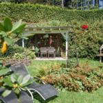 Garten mit Pavillon, Liegestühlen und Grillplatz.