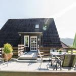 Haus mit Terrasse, Tisch, Stühlen und grünem Sonnenschirm