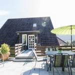 Haus mit Terrasse, Tisch, Stühlen und grünem Sonnenschirm