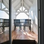 Terrasse mit Tisch und Stühlen unter Dachkonstruktion mit Holzboden