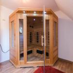 Eine Sauna mit Holzverkleidung und Glaswänden in einem Raum mit Holzboden und schräger Decke.