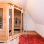 Sauna mit Holzverkleidung und Glasfront in einem Dachbodenraum mit rotem Teppich.