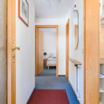 Flur mit Schlafzimmer und Küche. Holztüren und roter Teppich.