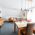 Wohn- und Essbereich mit Tisch, Stühlen, Sofa und TV.