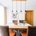 Esszimmer mit Holztisch, Stühlen und hängenden Lampen.