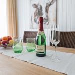 Tisch mit Flasche, Gläsern und Obst auf Tischdecke.