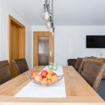 Esszimmer mit Holztisch, Stühlen und Fernseher an der Wand.