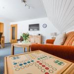 Wohnzimmer mit Sofa, Tisch und Fernseher unter schrägem Dach