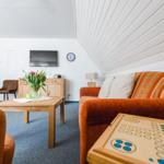 Wohnzimmer mit Sofa, Couchtisch und Fernseher unter schräger Decke.