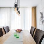 Esszimmer mit Holztisch, Stühlen und Deckenleuchte. An der Wand hängt ein Bild.