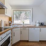 Küche mit Holzoberflächen, Fenster zum Wald und moderner Ausstattung.