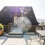 Haus mit Terrasse, Tisch und Stühlen, Pflanze und Bergblick.