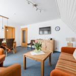 Wohnbereich mit Sofa, Sessel und Esstisch unter schrägem Dach