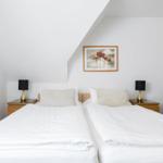 Zwei Betten mit weißen Bettwäsche, Nachttische und Bilder an der Wand.