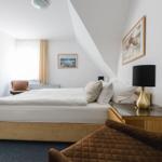 Schlafzimmer mit Dachschräge, Bett, Nachttisch und Sessel.