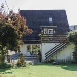 Haus mit Terrasse, Garten und Holztreppe zur oberen Etage.
