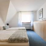 Zimmer mit Doppelbett, Fenster und Holzschrank