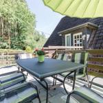 Terrasse mit Tisch, Stühlen und grünem Sonnenschirm vor einem Haus.