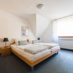 Schlafzimmer mit Doppelbett, zwei Nachttischen und Fenster mit Vorhängen.