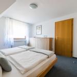 Schlafzimmer mit Dachschräge, Bett, Kleiderschrank und Fenster.