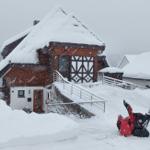 Snow-covered house with red snow blower in foreground