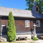 Wooden church with cross and benches in greenery