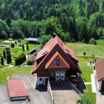 House with red roof, large garden, and forest in the background.