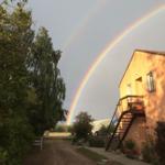 Ein Haus mit Balkon und Treppe unter einem Regenbogen.