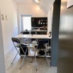 Küche mit Esstisch und Stühlen, Fenster und Schränke sichtbar.