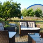 Außenbereich mit Rattanmöbeln, Pflanzen und großem Zelt im Hintergrund.