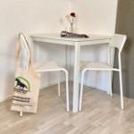 Weißer Tisch mit zwei Stühlen und Blumen in Vase