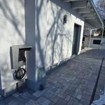 Außenbereich mit Ladesäule und gepflastertem Weg an modernem Haus