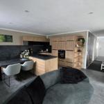 Wohnküche mit Holzmöbeln, grauem Sofa und Küchentisch mit Stühlen.