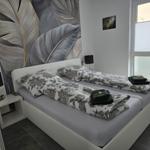 Schlafzimmer mit Doppelbett, floraler Bettwäsche und großen Fenstern.