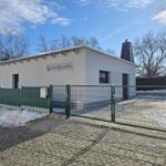 Modernes Gartenhaus mit Gittertor und Schneeflächen.