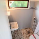 Bathroom with sink, toilet, and shower under window