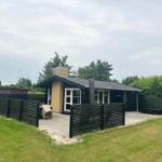 Modern villa with terrace, garden, and wooden fence. Entrance door and windows are visible.