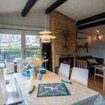 Dining area with table, chairs, and fireplace. Living area with sofa and window.