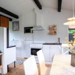 Kitchen with white built-in cabinetry, dining table, and seating. Wooden floor and black beams.