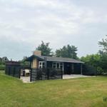 A simple house with garden and terrace, surrounded by trees.