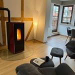 Wohnzimmer mit Kaminofen, Sessel und Blick auf Essbereich.