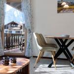 Essbereich mit Tisch und Stühlen. Blick auf Balkon und Berge.