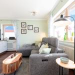 Wohnzimmer mit Sofa, Couchtisch und Fernseher. Fenster mit Blick auf Berge.