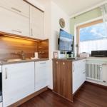 Küche mit Holzoptik, Fenster mit Bergblick und TV-Wand