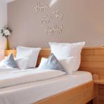 Schlafzimmer mit Holzbett, weißen Kissen und Wanddekoration.